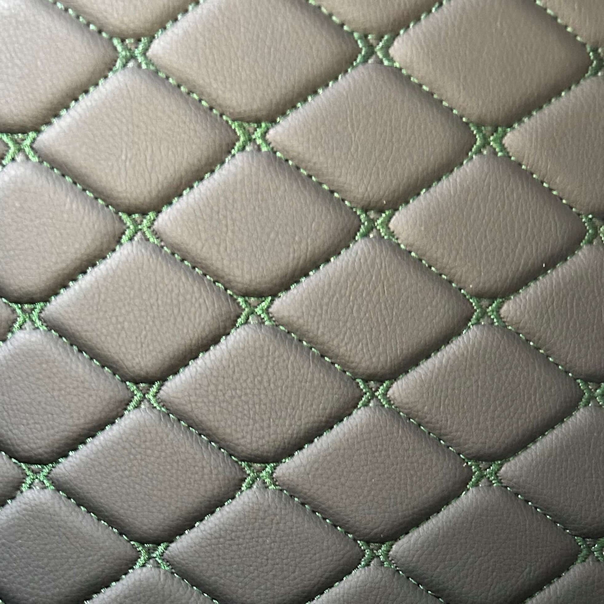 Close-up of diamond-stitched car mat material in gray with green stitching details.
