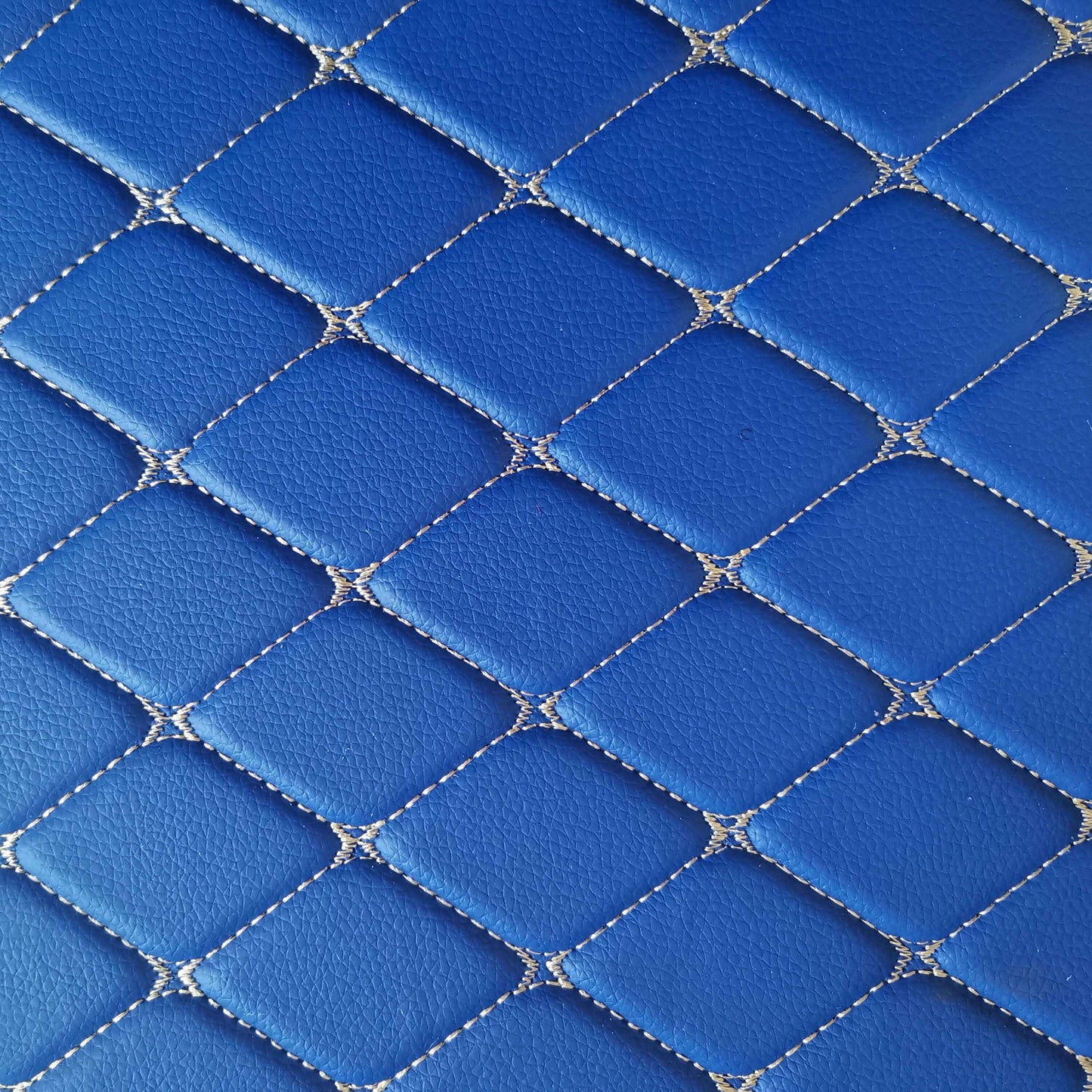 Close-up view of a blue diamond-stitched leather pattern, showcasing intricate design and craftsmanship.