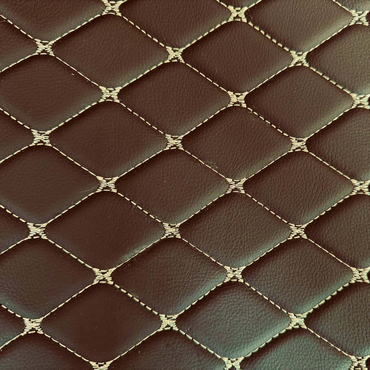 Close-up of luxurious diamond-stitched brown leather texture for car mats.