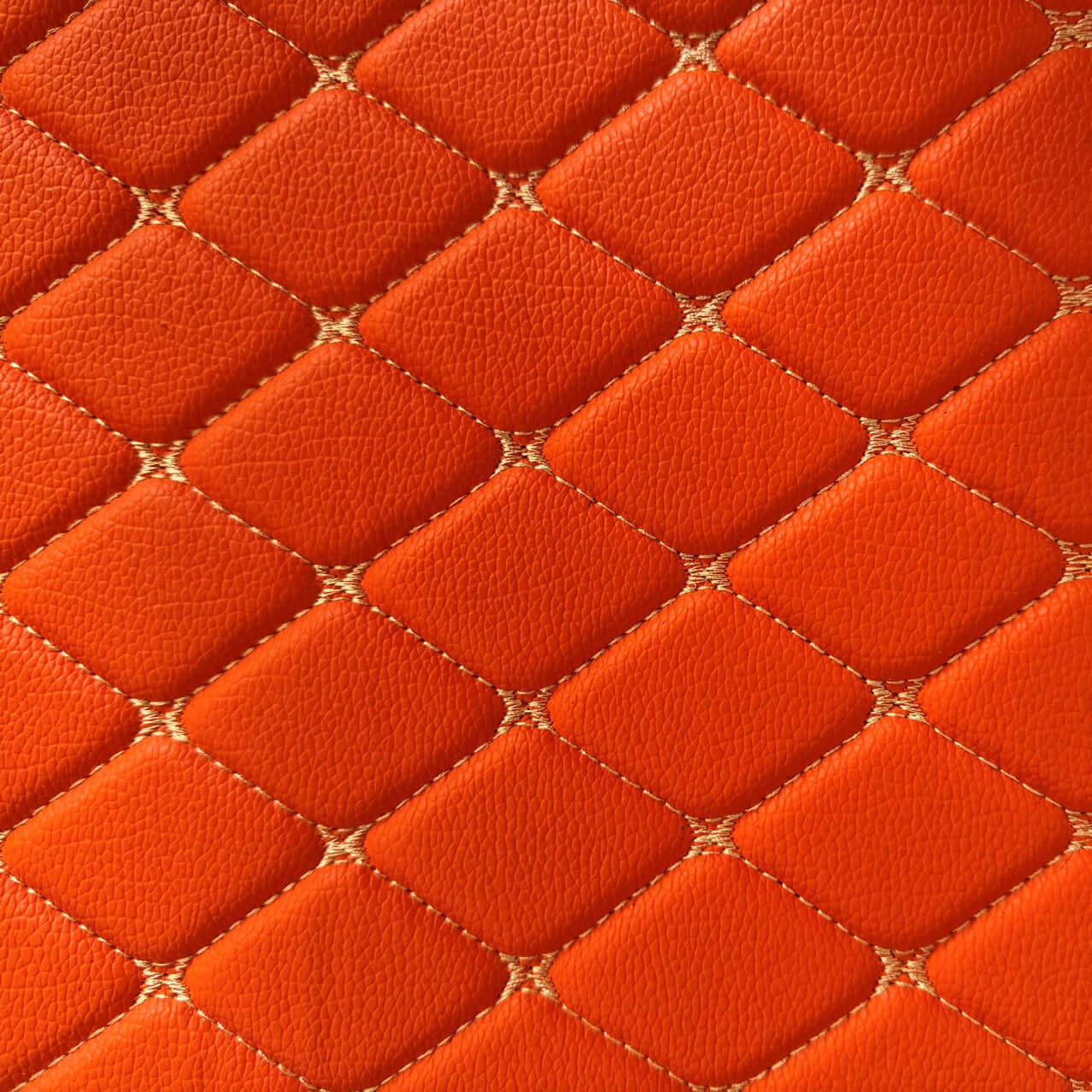 Close-up of diamond-stitched orange leather texture, showcasing a luxurious and modern design.