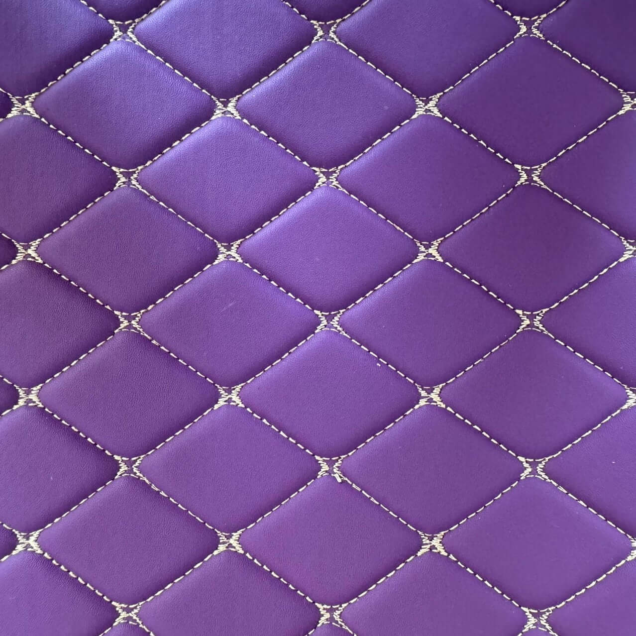 Close-up of a purple diamond-stitched texture with white detailing, ideal for car interior mats.