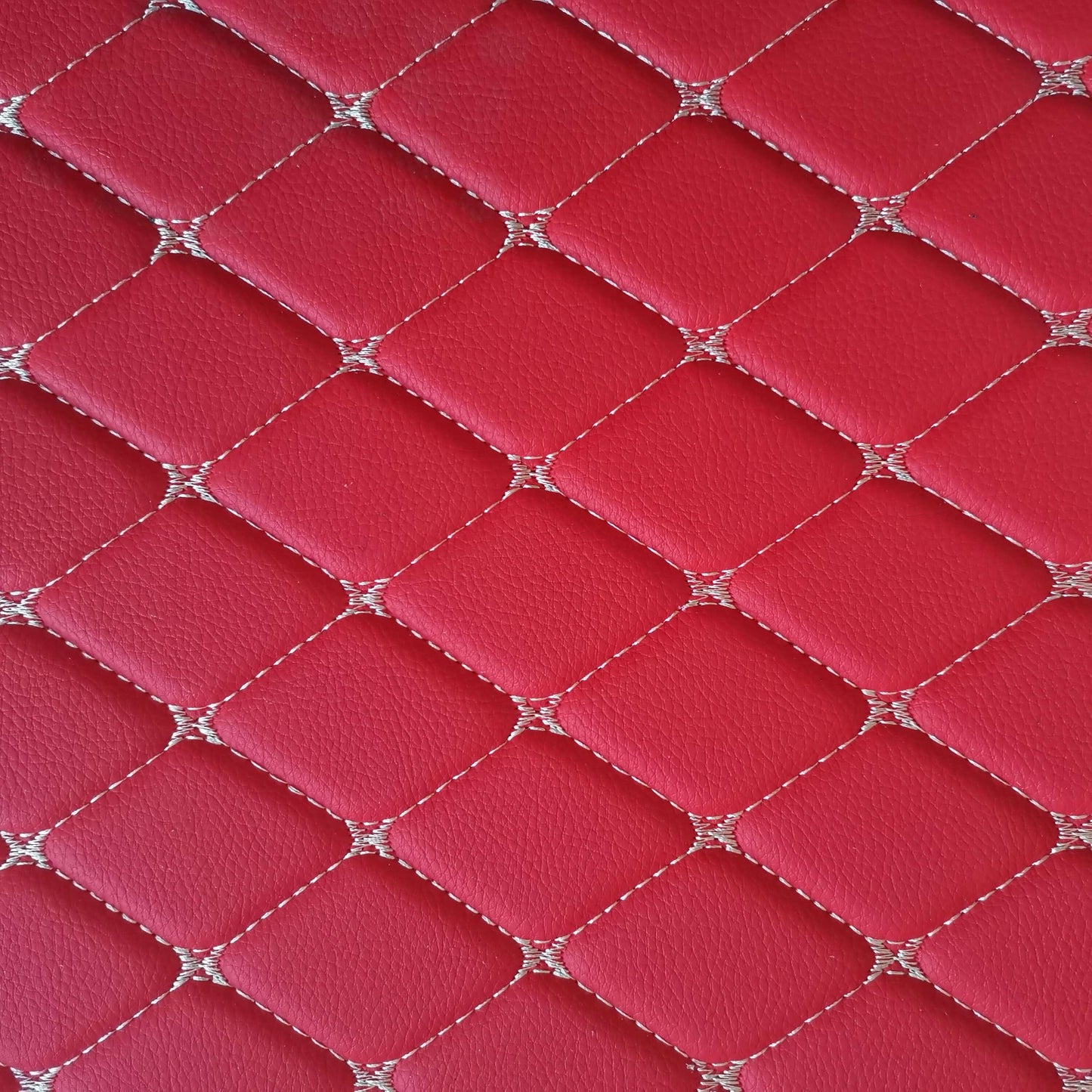 Close-up view of diamond-stitched red leather pattern for car mats or interior design.